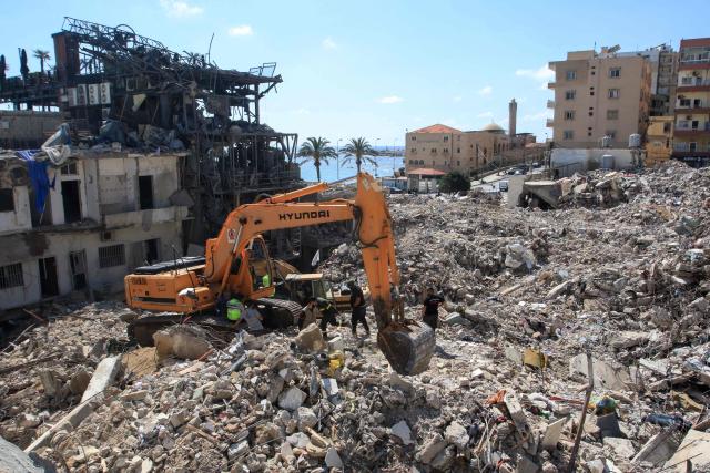 A digger removes the rubble of buildings destroyed in Israeli strikes, as the search for survivors buried underneath continues in the southern Lebanese coastal city of Tyre on April 21, 2026. Israeli defence minister said on April 21 that his country's campaign in Lebanon relied on both military and diplomatic pressure to disarm Iran-allied Hezbollah. Though a truce between Israel and Lebanon took effect on April 17, Israeli troops are still present and actively fighting Hezbollah militants in Lebanon's south. (Photo by Mahmoud ZAYYAT / AFP)