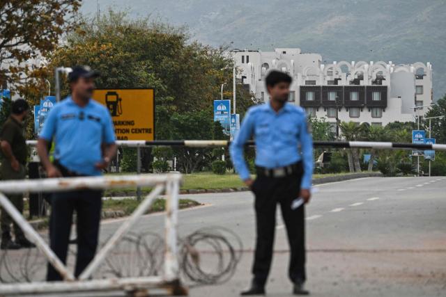 Security personnel stand guard at a checkpoint near the Serena Hotel, that hosted the first round of US-Iran negotiations during the Middle East war, at the Red Zone area in Islamabad on April 21, 2026, amid heightened security measures ahead of anticipated second round of US-Iran peace talks. Mediator Pakistan has yet to receive a formal response from Iran on whether it would send a delegation for a second round of talks with the United States, Islamabad's information minister said on April 21. (Photo by Asif HASSAN / AFP)