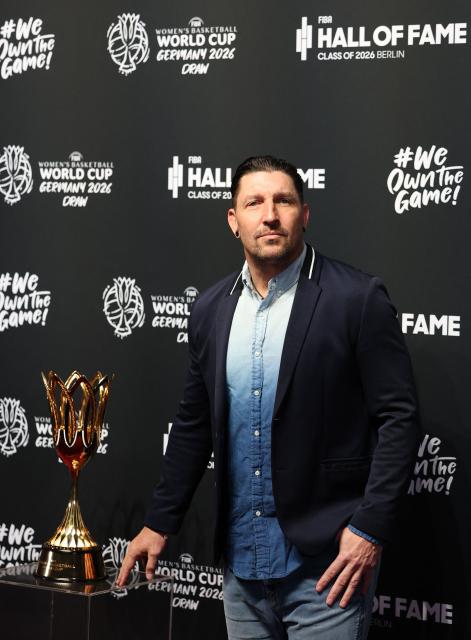 German handball player Stefan Kretzschmar poses next to the FIBA Women's Basketball World Cup trophy to the FIBA Women's Basketball 2026 World Cup draw in Berlin on April 21, 2026. The final round of the 2026 FIBA Women's Basketball World Cup is scheduled to take place in September in Berlin. (Photo by Odd ANDERSEN / AFP)