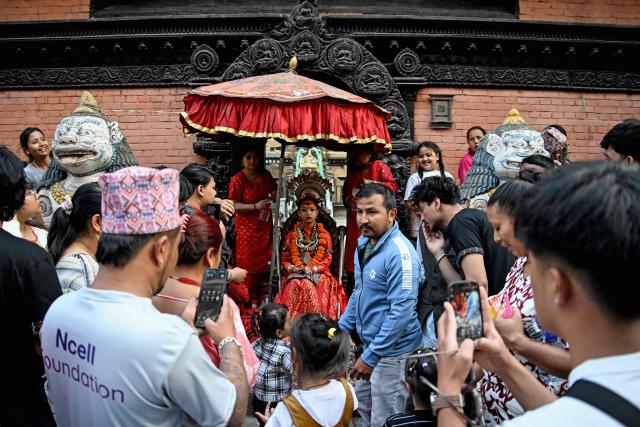 Devotees take pictures of a girl revered as living goddess 'Kumari' (C) during the first day of the Rato Machindranath Jatra festival in Lalitpur on April 21, 2026. (Photo by Prakash MATHEMA / AFP)