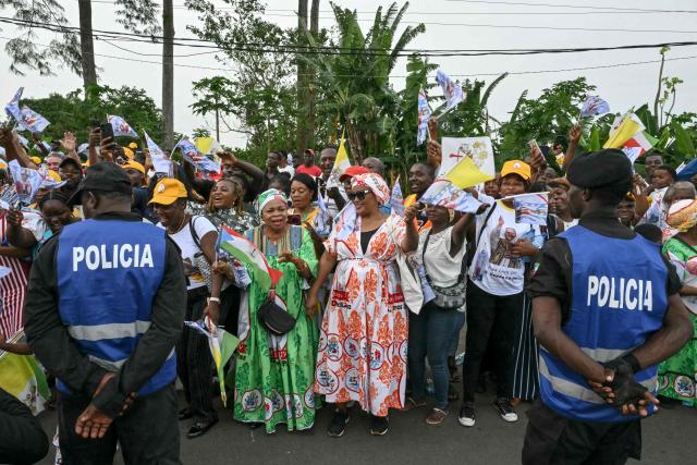Residents gather next to the road where the motorcade of Pope Leo XIV will pass on his way to visits the staff and patients of the "Jean Pierre Olie" Psychiatric Hospital in Malabo on the ninth day of an 11-day apostolic journey to Africa, on April 21, 2026. (Photo by Alberto PIZZOLI / AFP)