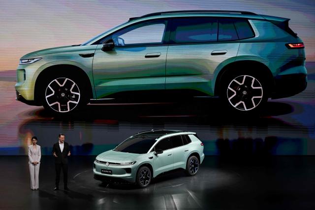 Volkswagen's new ID. AURA T6 electric SUV model is presented by CEO of Volkswagen Passenger Cars Thomas Schafer (R) at an event ahead of the Beijing Auto Show 2026 in Beijing on April 21, 2026. (Photo by Pedro PARDO / AFP)