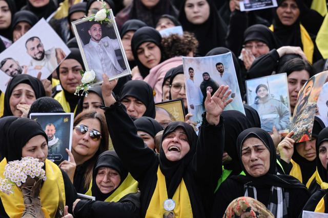 Mourners hold up portraits of Hezbollah fighters killed before a 10-day ceasefire was agreed between the Iran-backed militant group and Israel during a mass funeral procession in the southern village of Kfar Sir on April 21, 2026. Israeli defence minister said on April 21 that his country's campaign in Lebanon relied on both military and diplomatic pressure to disarm Iran-allied Hezbollah. Though a truce between Israel and Lebanon took effect on April 17, Israeli troops are still present and actively fighting Hezbollah militants in Lebanon's south. (Photo by Anwar AMRO / AFP)