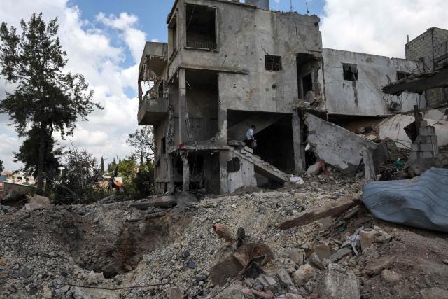 A man carries personal belongings from a building destroyed in an Israeli strike in the southern Lebanese village of Kfar Sir on April 21, 2026. Israeli defence minister said on April 21 that his country's campaign in Lebanon relied on both military and diplomatic pressure to disarm Iran-allied Hezbollah. Though a truce between Israel and Lebanon took effect on April 17, Israeli troops are still present and actively fighting Hezbollah militants in Lebanon's south. (Photo by Anwar AMRO / AFP)