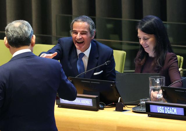 Argentine diplomat Rafael Mariano Grossi (C), accompanied by the president of the UN General Assembly Annalena Baerbock (R), is greeted at the start of a hearing to be considered as the next United Nations' Secretary General at the UN Headquarters in New York, on April 21, 2026. Grossi is among four candidates vying for the position currently held by Portugal's Antonio Guterres. (Photo by TIMOTHY A. CLARY / AFP)