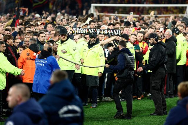 Supporters of Lens celebrate on the pitch after their team's victory at the end of the French Cup semi-final football match between and RC Lens and Toulouse FC at the Stade Bollaert-Delelis in Lens, northern France on April 21, 2026. (Photo by Sameer AL-DOUMY / AFP)