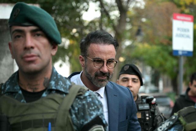 Argentine neurosurgeon Leopoldo Luque is escorted by police officers as he leaves the court hall for a trial hearing on Argentine football legend Diego Maradona's death in San Isidro, Buenos Aires province, Argentina on April 21, 2026. Diego Maradona's daughter Gianinna on April 21, 2026, slammed what she called the "total manipulation" of the late player's family by his doctors in the lead-up to his death in 2020. (Photo by Juan MABROMATA / AFP)