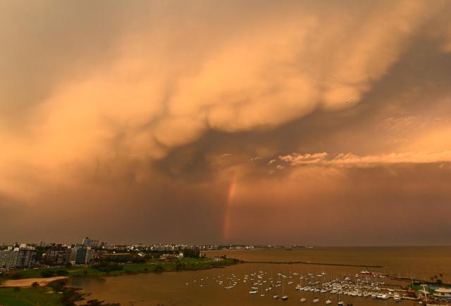 A rainbow and a mammatus cloud formation lit by the setting sun are seen in Montevideo on April 21, 2026. (Photo by Mariana SUAREZ / AFP)