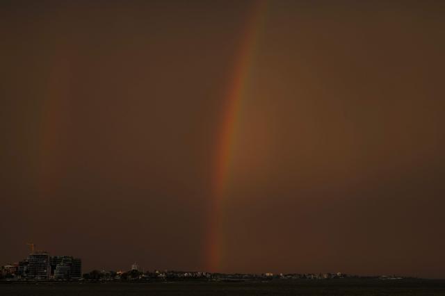 A rainbow is seen as the sun sets after rainfall in Montevideo on April 21, 2026. (Photo by Eitan ABRAMOVICH / AFP)