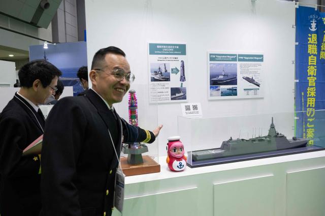 A member of the Japanese Maritime Self Defence Force (JMSDF) team showcases some of their technology at their booth at the Sea Japan Maritime Exhibition and Conference in Tokyo on April 22, 2026. Japan will ease decades-old arms export curbs, the government said Tuesday, in a major policy shift that paves the way for the sale of lethal weapons overseas as Tokyo ramps up its defence ambitions. The new rules end Japan's self-imposed curb on sales of lethal arms as Tokyo seeks to enter the international arms market, hoping to bolster national defence as well as boost economic growth. (Photo by Andrew CABALLERO-REYNOLDS / AFP)
