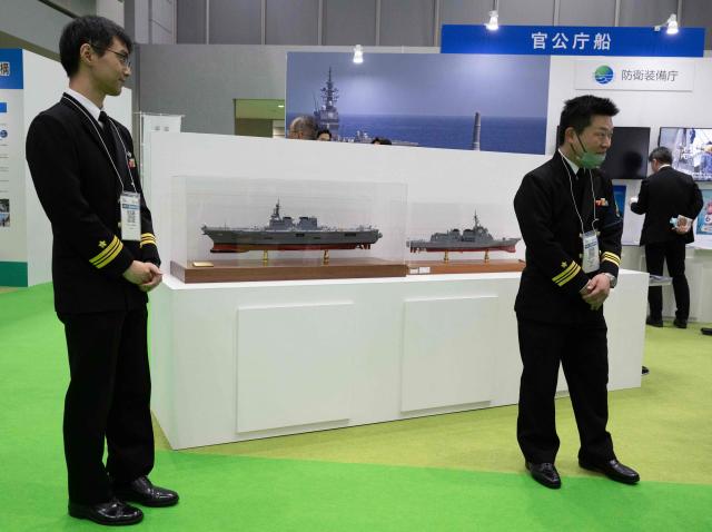 Members of the Japanese Maritime Self Defence Force (JMSDF) team wait for attendees to visit their booth at the Sea Japan Maritime Exhibition and Conference in Tokyo on April 22, 2026. Japan will ease decades-old arms export curbs, the government said Tuesday, in a major policy shift that paves the way for the sale of lethal weapons overseas as Tokyo ramps up its defence ambitions. The new rules end Japan's self-imposed curb on sales of lethal arms as Tokyo seeks to enter the international arms market, hoping to bolster national defence as well as boost economic growth. (Photo by Andrew CABALLERO-REYNOLDS / AFP)