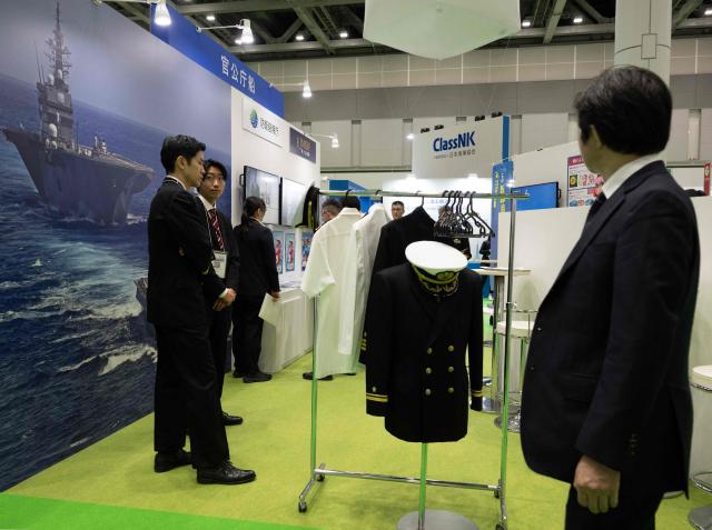 An attendee looks at a display by the Japanese Maritime Self Defence Force (JMSDF) group at the Sea Japan Maritime Exhibition and Conference in Tokyo on April 22, 2026. Japan will ease decades-old arms export curbs, the government said Tuesday, in a major policy shift that paves the way for the sale of lethal weapons overseas as Tokyo ramps up its defence ambitions. The new rules end Japan's self-imposed curb on sales of lethal arms as Tokyo seeks to enter the international arms market, hoping to bolster national defence as well as boost economic growth. (Photo by Andrew CABALLERO-REYNOLDS / AFP)