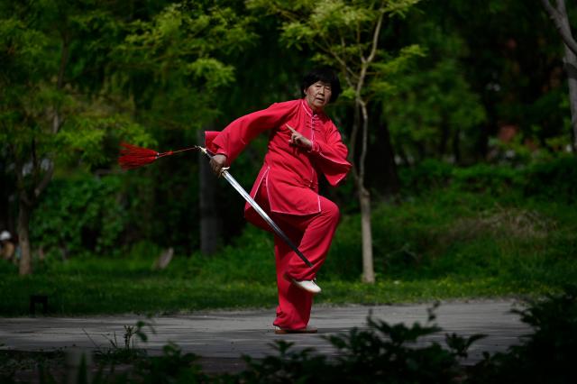 A woman performs Tai Chi along a road in Beijing on April 22, 2026. (Photo by WANG Zhao / AFP)
