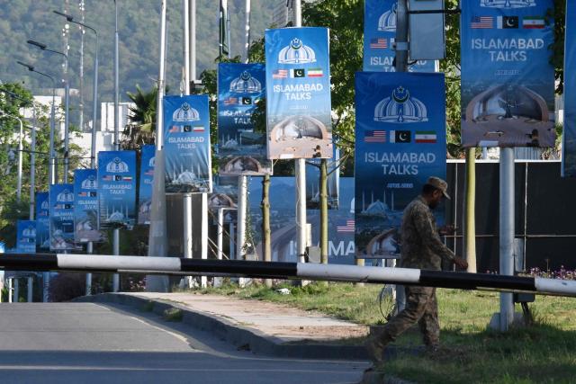 An army soldier walks past posters highlighting Pakistan's mediation of Iran–US peace talks near the Serena Hotel at the Red Zone area in Islamabad on April 22, 2026. Pakistani Prime Minister Shehbaz Sharif thanked US President Donald Trump on April 22, for extending a ceasefire with Iran that had been soon set to expire and urged both sides to continue talks. (Photo by Aamir QURESHI / AFP)