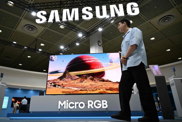 A man walks past Samsung 115" Micro RGB TV at the Samsung booth during the 2026 World IT Show in Seoul on April 22, 2026. (Photo by Jung Yeon-je / AFP)