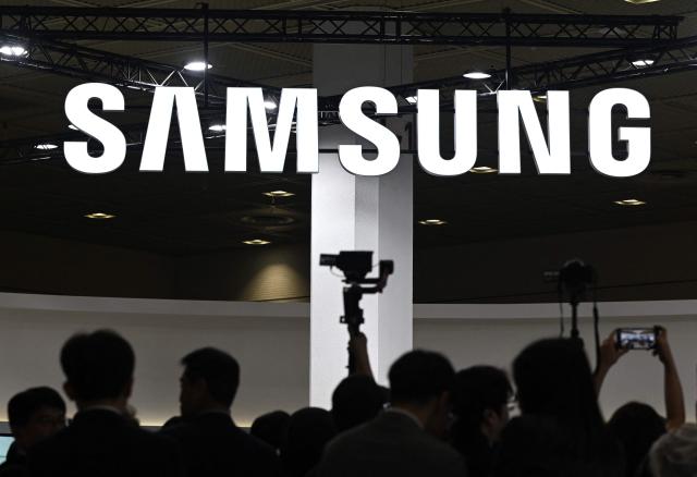 Visitors walk past the logo of Samsung Electronics during the 2026 World IT Show in Seoul on April 22, 2026. (Photo by Jung Yeon-je / AFP)