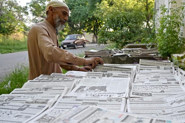 A hawker sorts newspapers early morning in Islamabad on April 22, 2026. (Photo by Asif HASSAN / AFP)