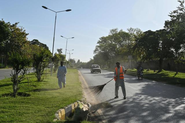 A municipal worker sweeps a street in Islamabad on April 22, 2026. (Photo by Asif HASSAN / AFP)
