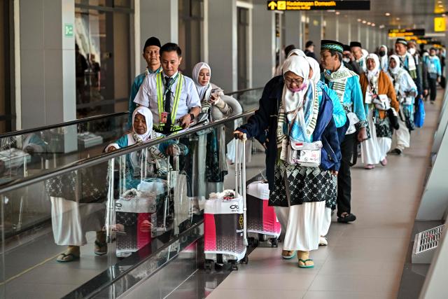 Pilgrims walk to their gate before heading to the holy city of Mecca to perform the annual hajj pilgrimage, at the Juanda International Airport in Sidoarjo on April 22, 2026. (Photo by JUNI KRISWANTO / AFP)