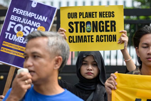 Environmental activists hold a protest urging the Indonesian government to demonstrate a commitment to a transition from fossil fuels in front of the Ministry of Energy and Mineral Resources (ESDM) office in Jakarta on April 22, 2026. (Photo by BAY ISMOYO / AFP)