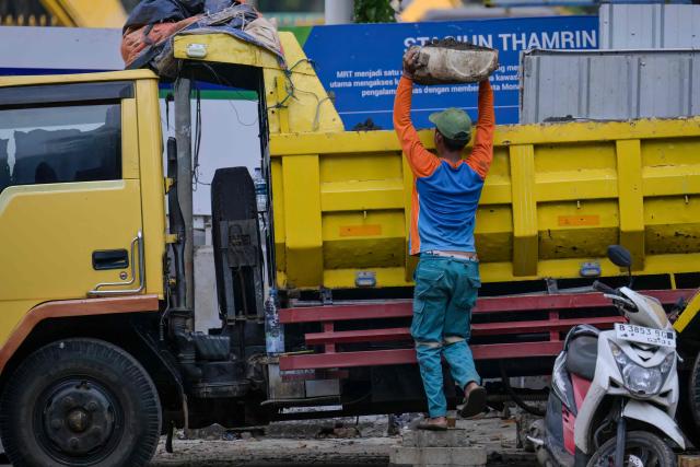 A labourer loads a truck with debris from a construction site in Jakarta on April 22, 2026. (Photo by BAY ISMOYO / AFP)