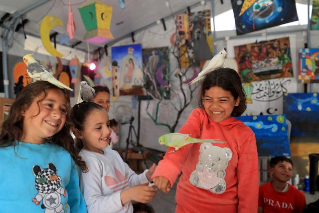 Displaced Palestinian children participate in psychological debriefing sessions at an art studio that uses pets and birds to aid the children, in the Al-Zawaida area, in the central Gaza Strip on April 21, 2026. (Photo by Eyad Baba / AFP)