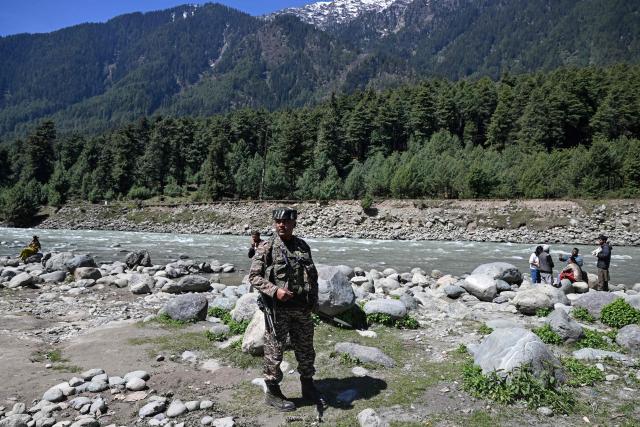 Tourists enjoy the view as an Indian paramilitary personnel patrols along the banks of Lidder river in Pahalgam, in south Kashmir's Anantnag district on April 22, 2026 that marks the first anniversary of the Pahalgam attack which killed 26 men, mostly Hindu tourists. (Photo by Tauseef MUSTAFA / AFP)