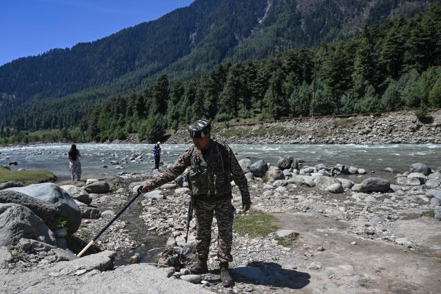 An Indian paramilitary personnel searches for explosives using a metal detector along the banks of Lidder river in Pahalgam, in south Kashmir's Anantnag district on April 22, 2026 that marks the first anniversary of the Pahalgam attack which killed 26 men, mostly Hindu tourists. (Photo by Tauseef MUSTAFA / AFP)