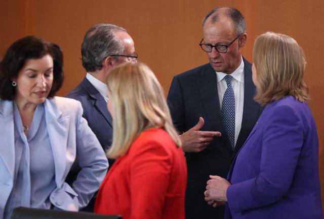 Germany's Chancellor Friedrich Merz (2nd R) talks with ministers as they arrive for the weekly cabinet meeting at the Chancellery in Berlin on April 22, 2026. (Photo by Odd ANDERSEN / AFP)
