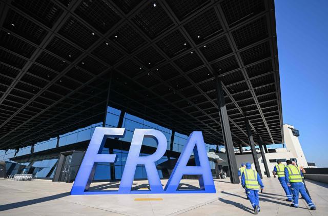 Security personnel walk past the letters FRA outside the new Terminal 3 of Frankfurt's international airport on the day of its official inauguration on April 22, 2026 in Frankfurt, western Germany. (Photo by Kirill KUDRYAVTSEV / AFP)