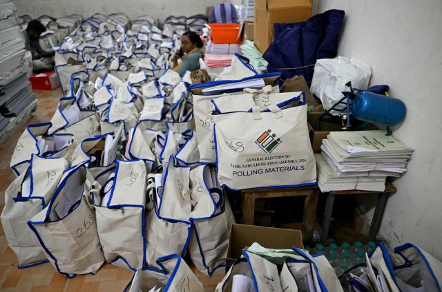 Election officials sit next to polling materials before they are dispatched to polling stations on the eve of the 2026 Tamil Nadu Legislative Assembly elections in Chennai on April 22, 2026. (Photo by R. Satish BABU / AFP)