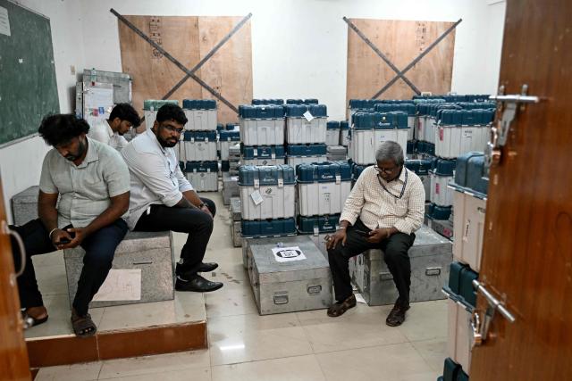 Election officials sit next to polling materials before they are dispatched to polling stations on the eve of the 2026 Tamil Nadu Legislative Assembly elections in Chennai on April 22, 2026. (Photo by R. Satish BABU / AFP)