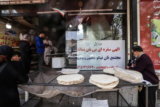 Iranian wait to buy freshly baked bread at a local bakery in the center of Tehran on April 22, 2026, amid a ceasefire in the region. Pakistan's capital was still locked in gear on April 22, to host high-stakes US-Iran talks that were pushed back at the last minute overnight, but many residents began to tire of the heavy personal and economic toll of tight security restrictions. (Photo by ATTA KENARE / AFP) / 