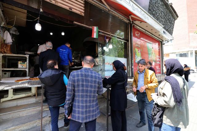 Iranian wait to buy freshly baked bread at a local bakery in the center of Tehran on April 22, 2026, amid a ceasefire in the region. Pakistan's capital was still locked in gear on April 22, to host high-stakes US-Iran talks that were pushed back at the last minute overnight, but many residents began to tire of the heavy personal and economic toll of tight security restrictions. (Photo by ATTA KENARE / AFP) / 