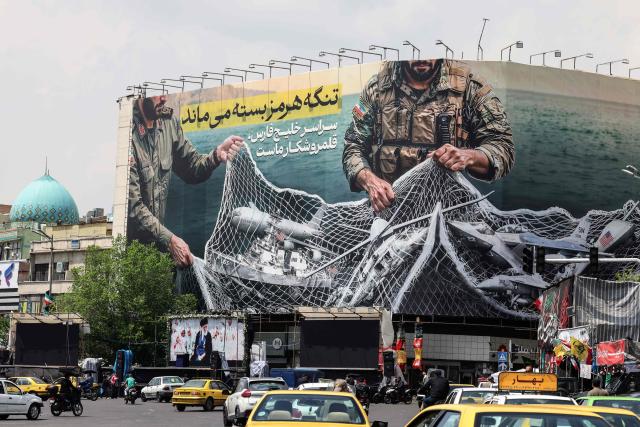 Vehicles drive past a giant billboard reading 'The Strait of Hormuz remains closed' at the Revolution Square in Tehran on April 22, 2026, amid a ceasefire in the region. Pakistan's capital was still locked in gear on April 22, to host high-stakes US-Iran talks that were pushed back at the last minute overnight, but many residents began to tire of the heavy personal and economic toll of tight security restrictions. (Photo by ATTA KENARE / AFP) / 