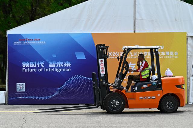 A worker drives a forklift ahead of the Beijing Auto Show 2026 at the China International Exhibition Center in Beijing on April 22, 2026. (Photo by Pedro PARDO / AFP)