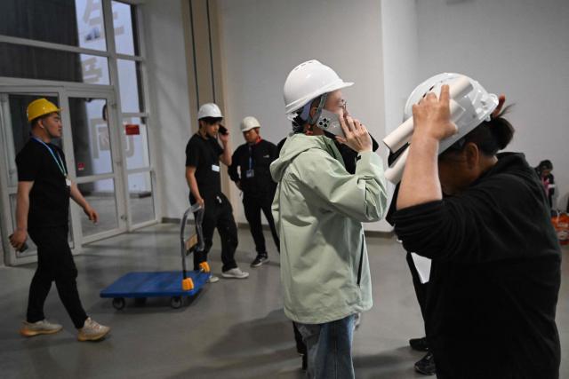 Workers assemble the venue ahead of the Beijing Auto Show 2026 at the China International Exhibition Center in Beijing on April 22, 2026. (Photo by Pedro PARDO / AFP)