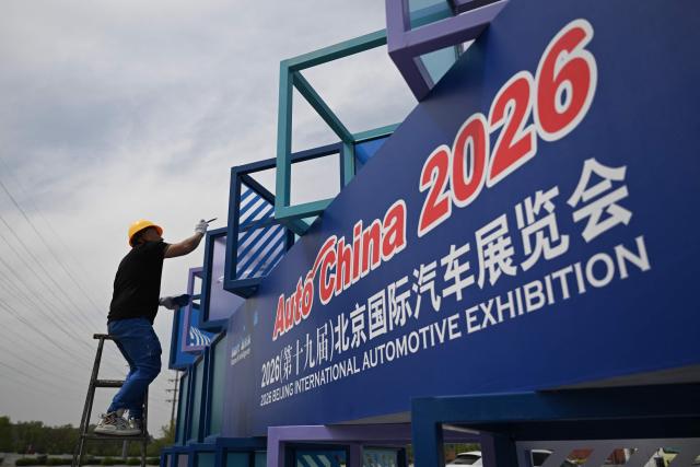 A worker puts the finishing touches on the venue ahead of the Beijing Auto Show 2026 at the China International Exhibition Center in Beijing on April 22, 2026. (Photo by Pedro PARDO / AFP)