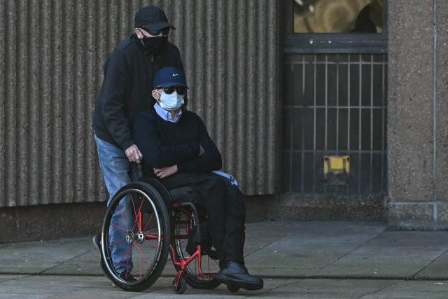 Mark Mogan, who is accused of racially abusing football player Antoine Semenyo - then with Bournemouth and now with Manchester City - during a match in August 2025, is pushed in a wheelchair as he arrives for his trial at the Liverpool Magistrates' Court in Liverpool, north-west England on April 22, 2026. (Photo by Paul ELLIS / AFP)