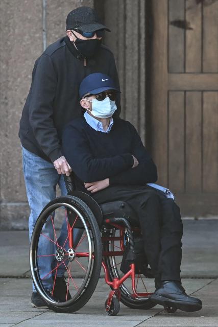 Mark Mogan, who is accused of racially abusing football player Antoine Semenyo - then with Bournemouth and now with Manchester City - during a match in August 2025, is pushed in a wheelchair as he arrives for his trial at the Liverpool Magistrates' Court in Liverpool, north-west England on April 22, 2026. (Photo by Paul ELLIS / AFP)
