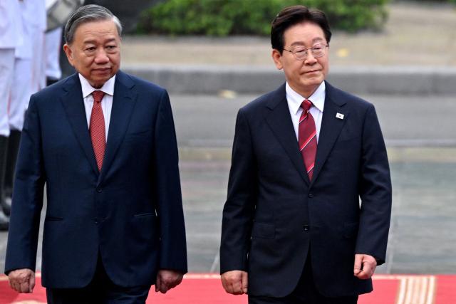 Vietnam's President To Lam (L) and South Korean President Lee Jae Myung (2nd R) review a guard of honor during a welcoming ceremony at the presidential palace in Hanoi on April 22, 2026. (Photo by Nhac NGUYEN / POOL / AFP)