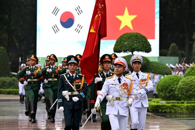 Members of a Vietnamese honour guard march during a welcome ceremony for South Korean President Lee Jae Myung at the Presidential Palace in Hanoi on April 22, 2026. (Photo by Nhac NGUYEN / POOL / AFP)