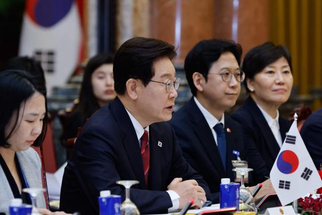 South Korean President Lee Jae Myung (C) speaks during a meeting with Vietnam's President To Lam at the Presidential Palace in Hanoi on April 22, 2026. Vietnam's top leader To Lam, who became president in early April assuming a dual role as head of state and of the ruling Communist Party, hosted South Korean President Lee Jae Myung in Hanoi on April 22, a meeting that was expected to yield multiple cooperative agreements. (Photo by LUONG THAI LINH / POOL / AFP)