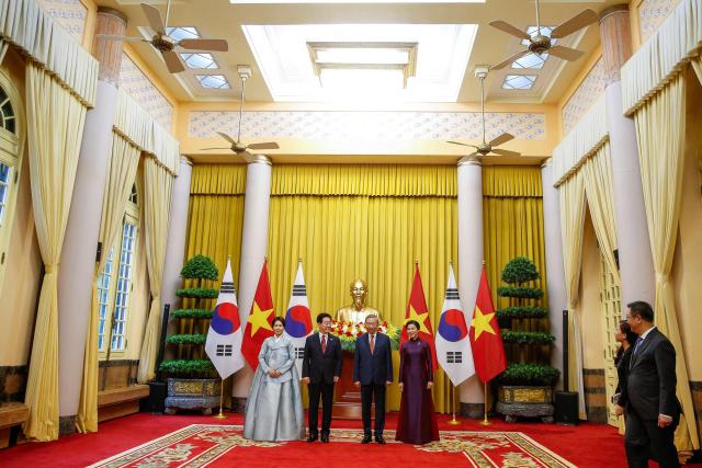 Vietnam's President To Lam (2nd R) and his wife Ngo Phuong Ly (R), South Korean President Lee Jae Myung (2nd L) and his wife Kim Hea Kyung (L) pose for a group photo at the Presidential Palace in Hanoi on April 22, 2026. Vietnam's top leader To Lam, who became president in early April assuming a dual role as head of state and of the ruling Communist Party, hosted South Korean President Lee Jae Myung in Hanoi on April 22, a meeting that was expected to yield multiple cooperative agreements. (Photo by LUONG THAI LINH / POOL / AFP)