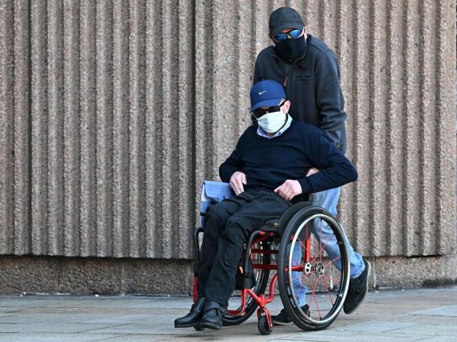 Mark Mogan, who is accused of racially abusing football player Antoine Semenyo - then with Bournemouth and now with Manchester City - during a match in August 2025, is pushed in a wheelchair as leaves Liverpool Magistrates' Court in Liverpool, north-west England on April 22, 2026, after case was adjourned until May 1. (Photo by Paul ELLIS / AFP)