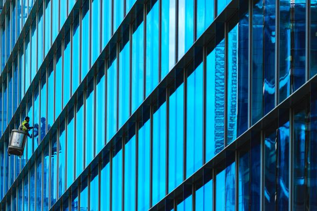 Workers suspended in a cradle clean the windows of an office building in Paddington Central in London on April 22, 2026. (Photo by ADRIAN DENNIS / AFP)
