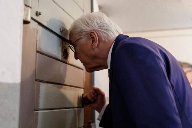 German President Frank-Walter Steinmeier peers into a detention cell as he visits the memorial site of the former Closed Youth Detention Centre (Geschlossener Jugendwerkhof Torgau - GJWH) in Torgau, eastern Germany on April 22, 2026. According to the memorial site, the closed youth detention centre used to be the only closed residential care facility in the GDR, where young people were to be re-educated into "socialist personalities" within just a few months. During the course of GDR history, approximately 135,000 children and young people were forced to go through socialist re-education practices in youth work camps and special children's homes. Historical traces at the memorial site are visible in the former solitary confinement cells and courtyard. (Photo by Jens SCHLÜTER / POOL / AFP)