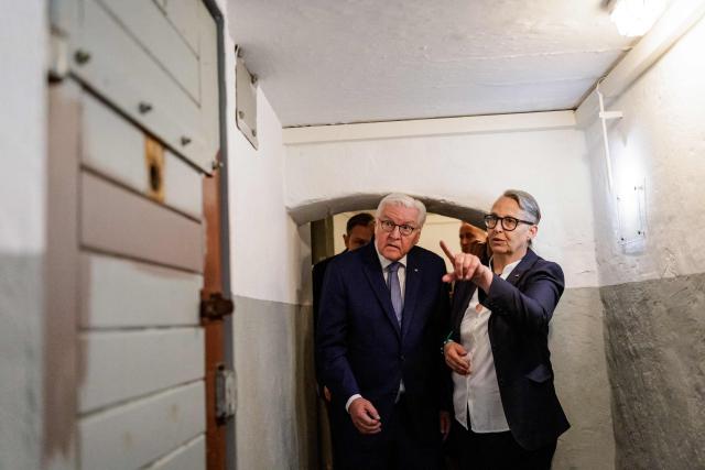 German President Frank-Walter Steinmeier is shown the hallway to the detention cells as he visits the memorial site of the former Closed Youth Detention Centre (Geschlossener Jugendwerkhof Torgau - GJWH) in Torgau, eastern Germany on April 22, 2026. According to the memorial site, the closed youth detention centre used to be the only closed residential care facility in the GDR, where young people were to be re-educated into "socialist personalities" within just a few months. During the course of GDR history, approximately 135,000 children and young people were forced to go through socialist re-education practices in youth work camps and special children's homes. Historical traces at the memorial site are visible in the former solitary confinement cells and courtyard. (Photo by Jens SCHLÜTER / POOL / AFP)