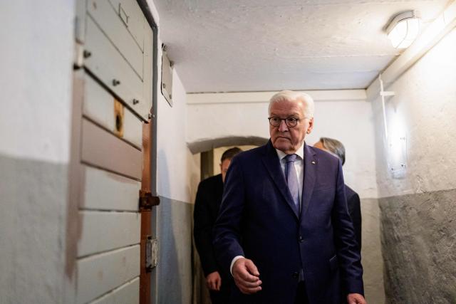 German President Frank-Walter Steinmeier walks down the hallway to the detention cells as he visits the memorial site of the former Closed Youth Detention Centre (Geschlossener Jugendwerkhof Torgau - GJWH) in Torgau, eastern Germany on April 22, 2026. According to the memorial site, the closed youth detention centre used to be the only closed residential care facility in the GDR, where young people were to be re-educated into "socialist personalities" within just a few months. During the course of GDR history, approximately 135,000 children and young people were forced to go through socialist re-education practices in youth work camps and special children's homes. Historical traces at the memorial site are visible in the former solitary confinement cells and courtyard. (Photo by Jens SCHLÜTER / POOL / AFP)