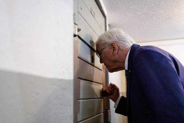 German President Frank-Walter Steinmeier peers into a detention cell as he visits the memorial site of the former Closed Youth Detention Centre (Geschlossener Jugendwerkhof Torgau - GJWH) in Torgau, eastern Germany on April 22, 2026. According to the memorial site, the closed youth detention centre used to be the only closed residential care facility in the GDR, where young people were to be re-educated into "socialist personalities" within just a few months. During the course of GDR history, approximately 135,000 children and young people were forced to go through socialist re-education practices in youth work camps and special children's homes. Historical traces at the memorial site are visible in the former solitary confinement cells and courtyard. (Photo by Jens SCHLÜTER / POOL / AFP)